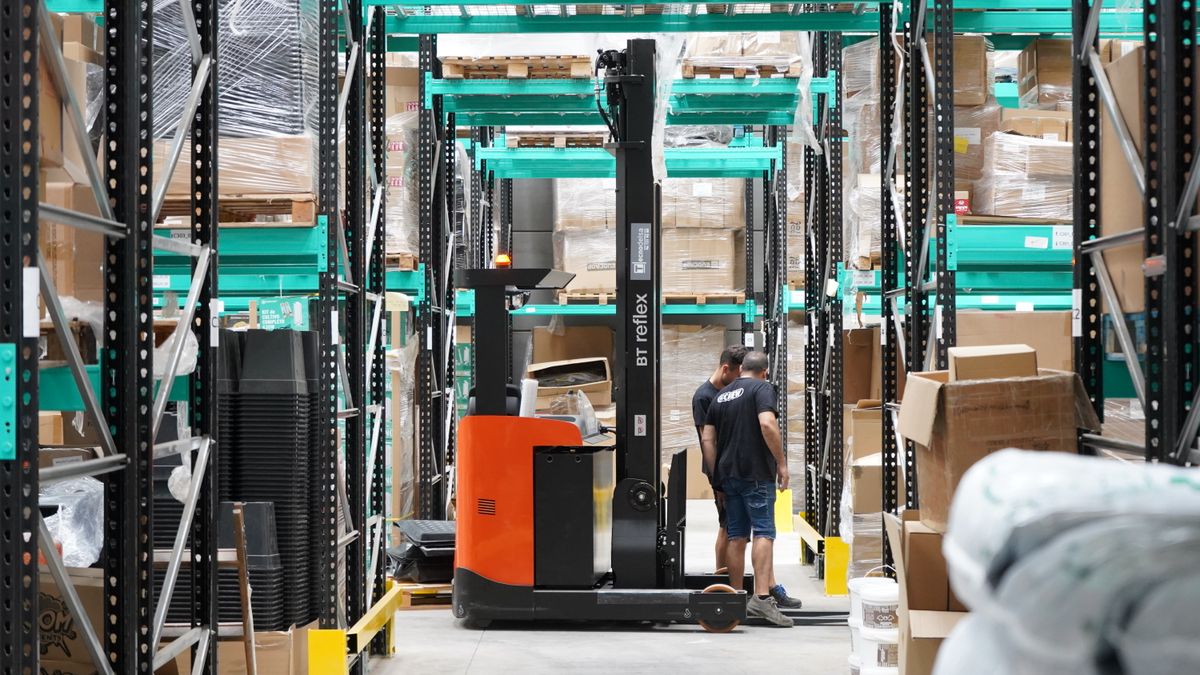 Warehouse workers beside a forklift and pallet storage racks